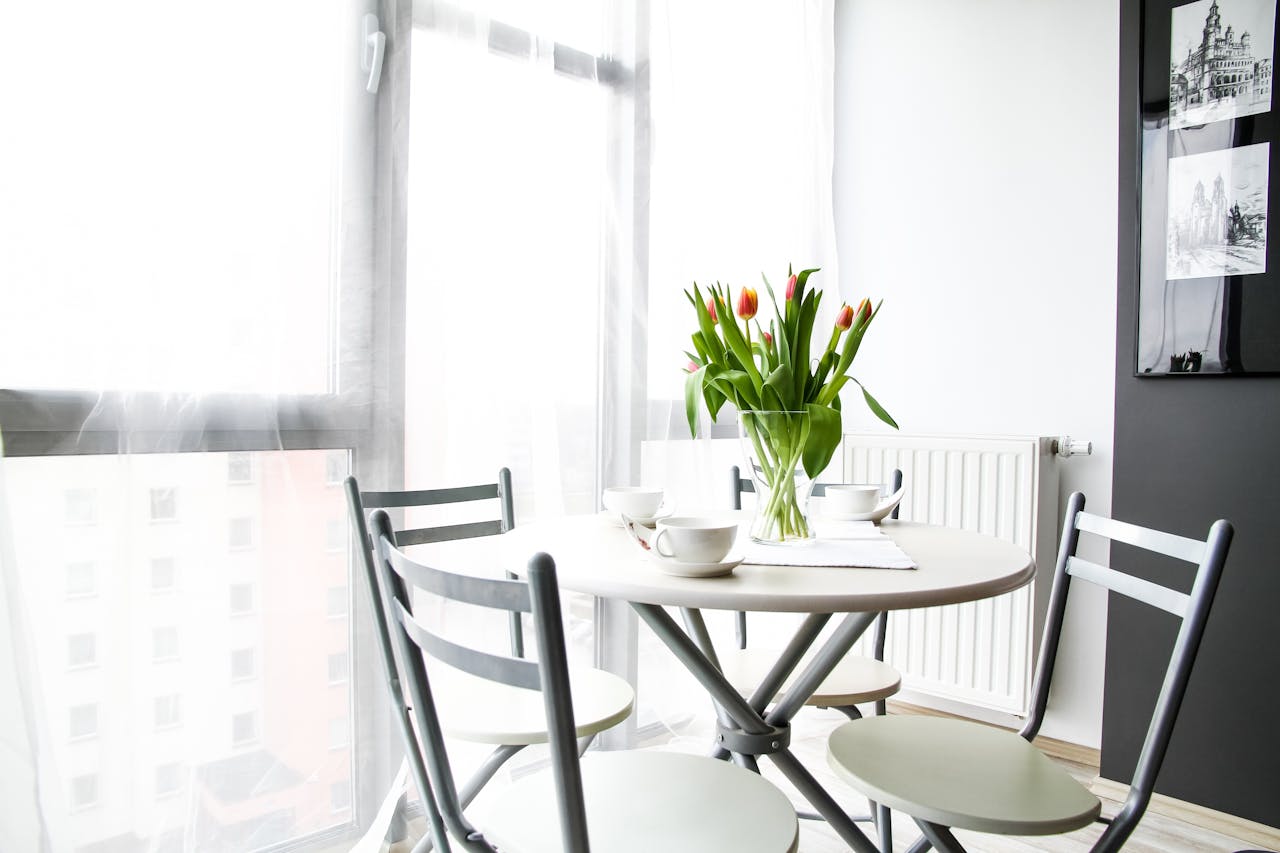 Bright dining space with table, chairs, tulips, and natural light through large windows.